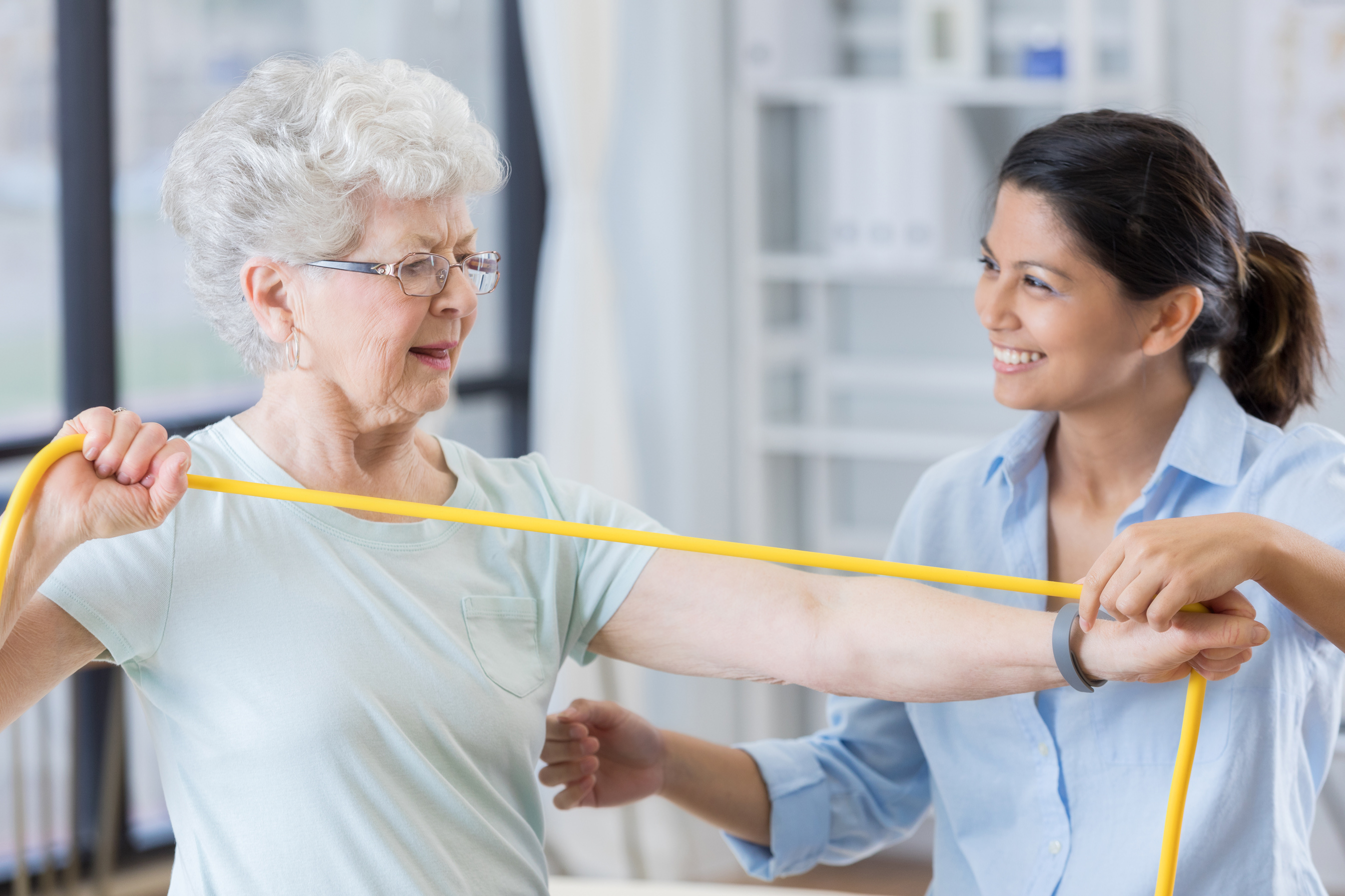 Senior physical therapy client uses resistance band